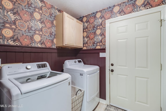 laundry area with wallpapered walls, a wainscoted wall, washer and dryer, and cabinet space