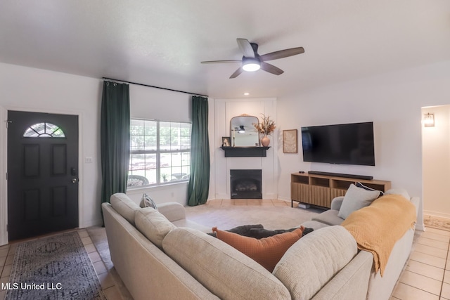living area featuring a fireplace, tile patterned floors, and ceiling fan
