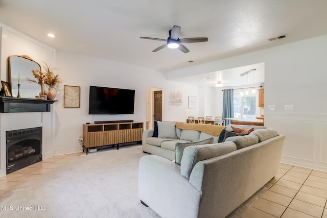 living room with light tile patterned flooring, a tiled fireplace, visible vents, and ceiling fan