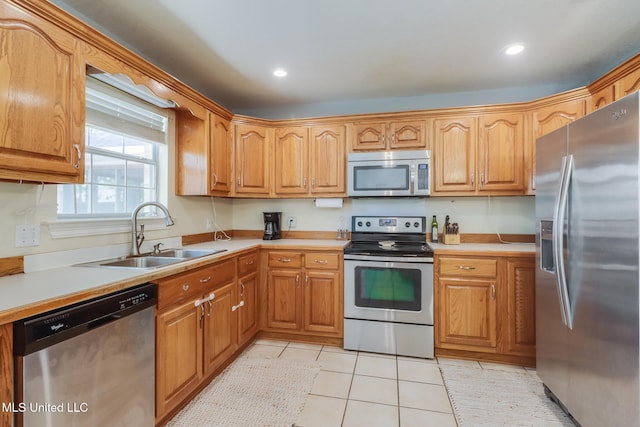 kitchen with a sink, recessed lighting, appliances with stainless steel finishes, light countertops, and light tile patterned floors