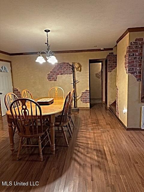 dining area featuring ornamental molding, a notable chandelier, wood finished floors, and a textured ceiling