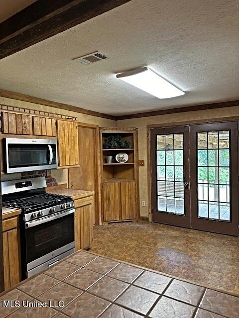 kitchen featuring brown cabinets, visible vents, appliances with stainless steel finishes, and a textured ceiling