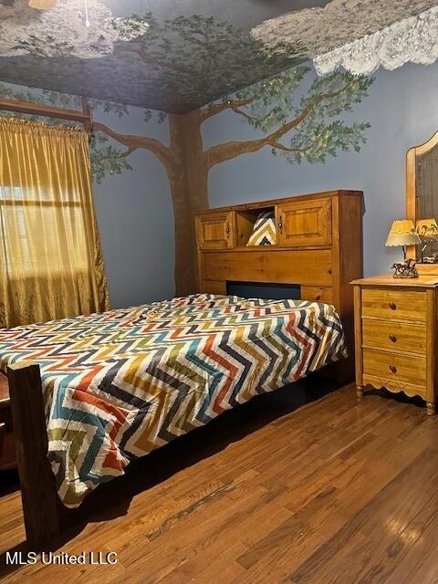 bedroom with arched walkways and wood finished floors