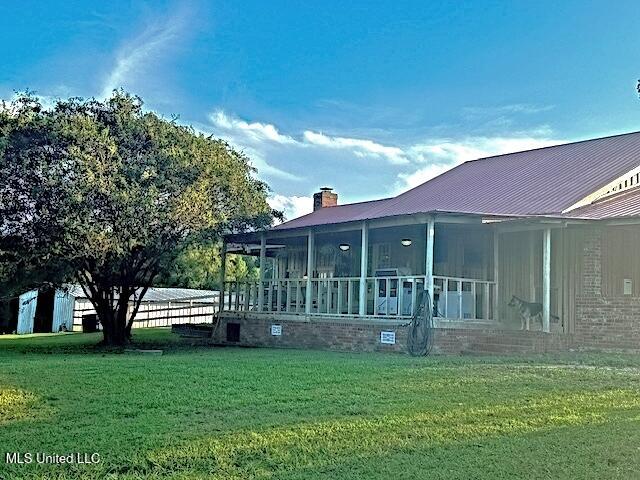 view of property exterior with a chimney, a sunroom, and a lawn