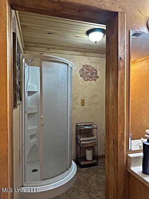 full bathroom with a shower stall and a textured wall