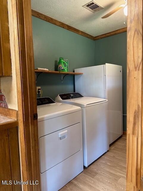 laundry area featuring laundry area, crown molding, light wood-style flooring, visible vents, and washing machine and clothes dryer
