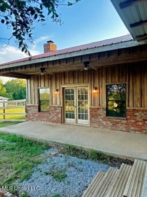 rear view of property featuring a chimney, ceiling fan, and brick siding