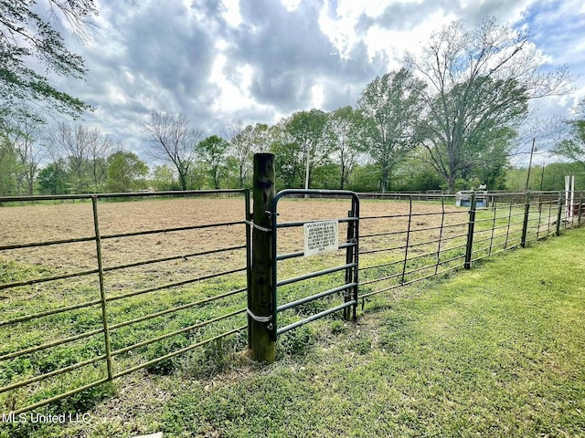 view of gate with fence and a rural view