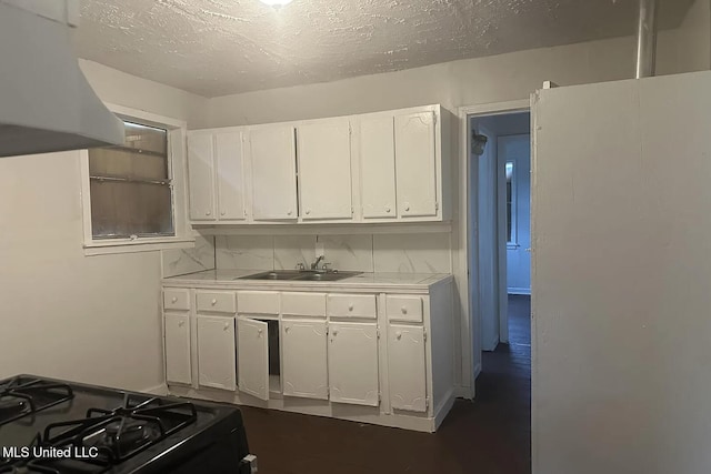 kitchen featuring black gas range oven, sink, white cabinetry, range hood, and a textured ceiling