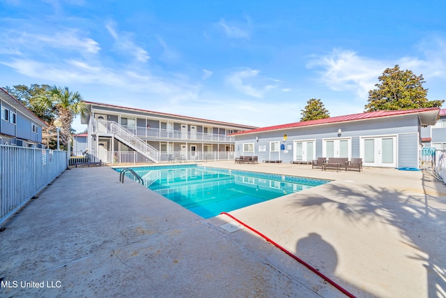 view of swimming pool with a fenced in pool, a patio area, fence, stairway, and french doors