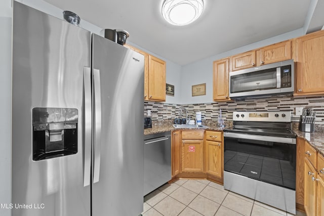 kitchen featuring light tile patterned floors, a sink, appliances with stainless steel finishes, and decorative backsplash