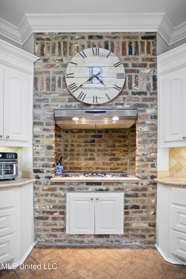 bar featuring stainless steel gas cooktop, exhaust hood, backsplash, and crown molding