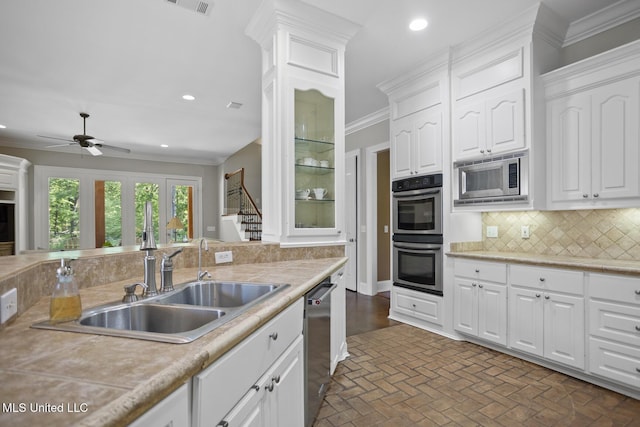 kitchen featuring backsplash, ornamental molding, stainless steel appliances, and white cabinets