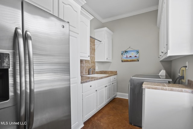 laundry room featuring crown molding, dark tile patterned floors, washer / clothes dryer, and a sink
