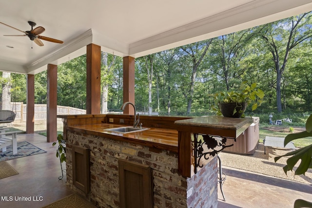 view of patio / terrace featuring an outdoor kitchen, a sink, fence, ceiling fan, and outdoor wet bar