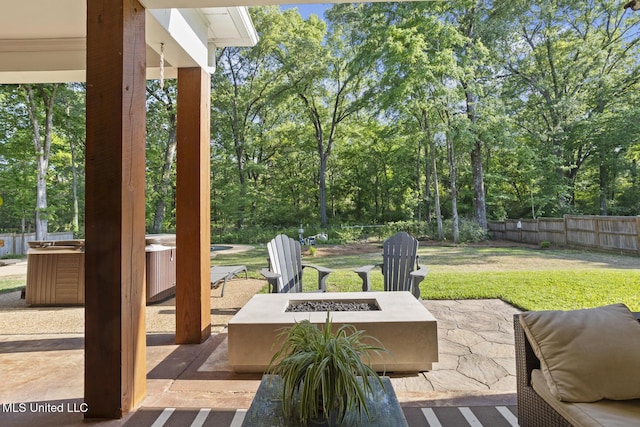 view of patio / terrace with a fenced backyard, a hot tub, and an outdoor fire pit