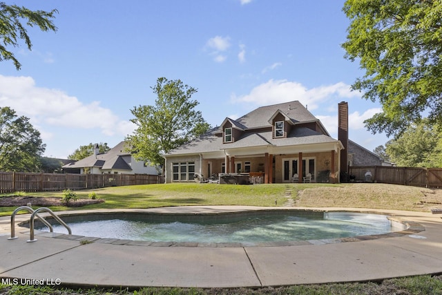 rear view of house with a chimney, french doors, a fenced backyard, a hot tub, and a yard
