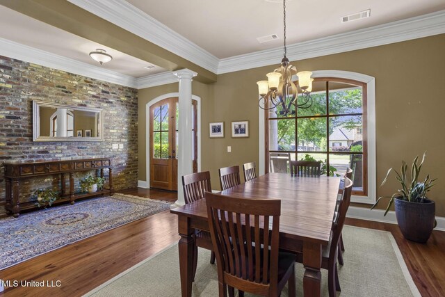 dining room with a chandelier, wood finished floors, visible vents, and ornate columns