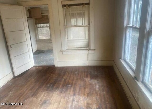 unfurnished room with dark wood finished floors and baseboards