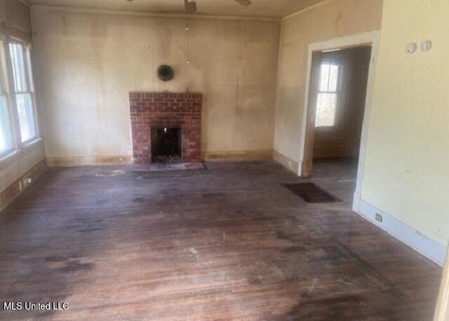 unfurnished living room featuring ceiling fan, a fireplace, baseboards, and dark wood finished floors