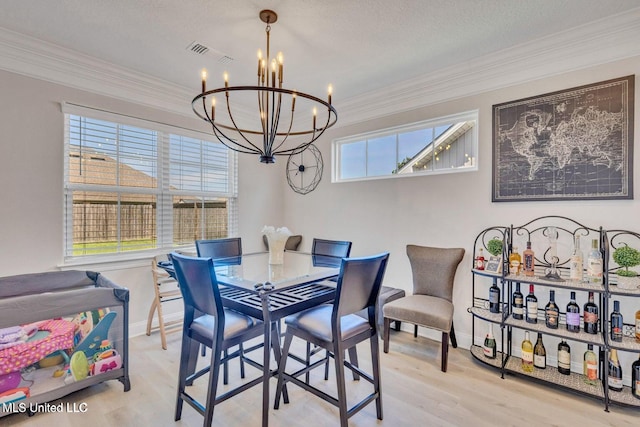 dining space featuring ornamental molding, visible vents, a notable chandelier, and wood finished floors