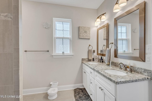 bathroom with double vanity, a sink, tile patterned floors, and baseboards