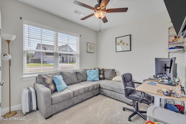office space featuring carpet flooring, baseboards, a textured ceiling, visible vents, and a ceiling fan