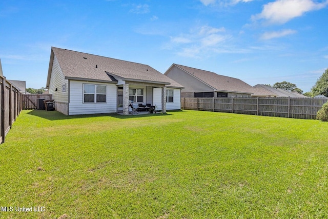 back of house with a lawn, a fenced backyard, and roof with shingles