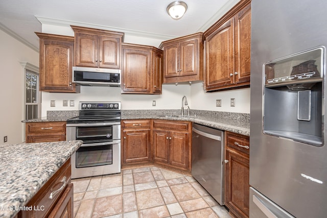 kitchen with sink, crown molding, light stone counters, and stainless steel appliances