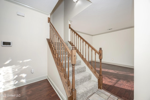 staircase with wood-type flooring and ornamental molding