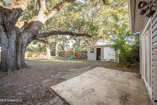 view of yard featuring an outdoor structure, a patio, and a playground