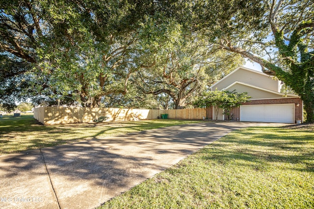 view of property hidden behind natural elements with a garage and a front lawn