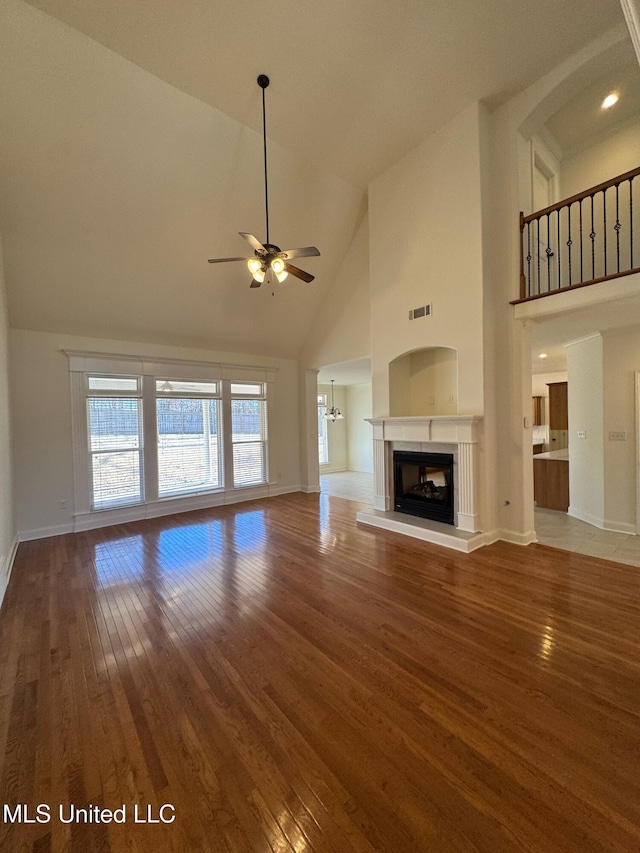 unfurnished living room with hardwood / wood-style flooring, high vaulted ceiling, and ceiling fan