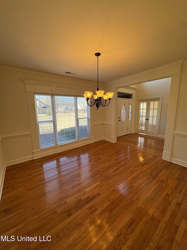 unfurnished dining area with a notable chandelier, a wealth of natural light, wood-type flooring, and french doors