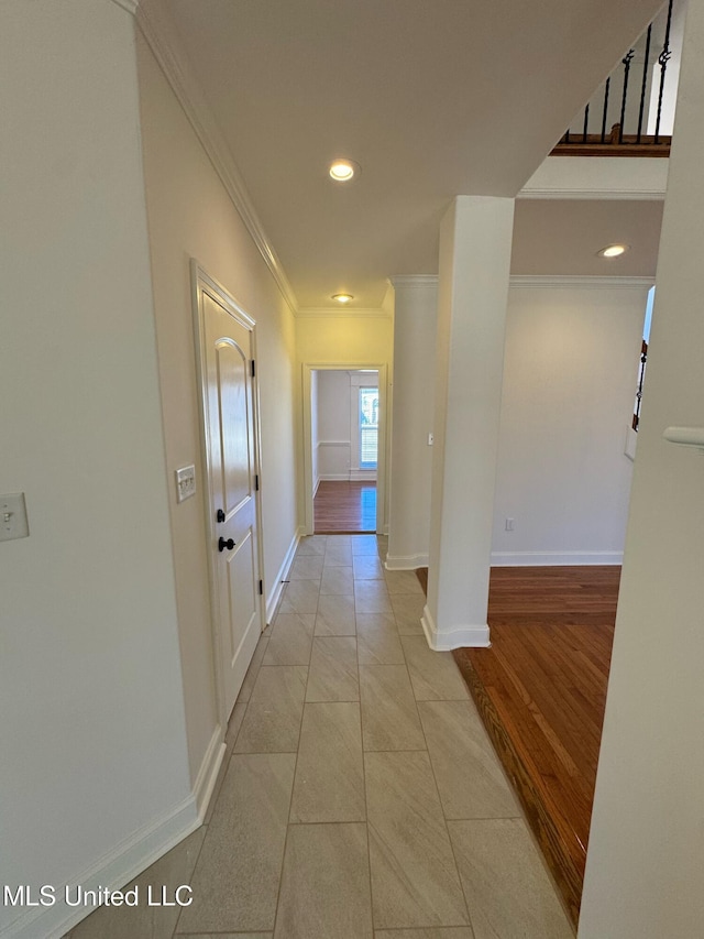 corridor with light tile patterned flooring and crown molding