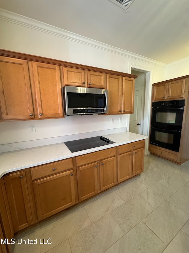 kitchen featuring light stone countertops, ornamental molding, and black appliances