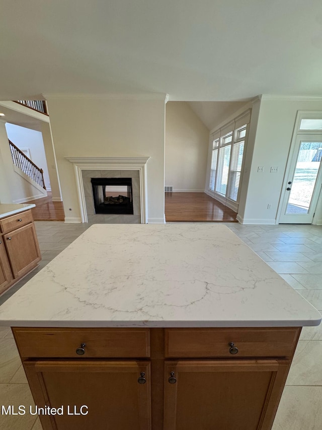 kitchen with a tile fireplace, light stone countertops, and light tile patterned flooring