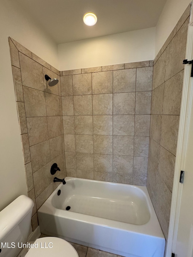 bathroom featuring tiled shower / bath combo and toilet