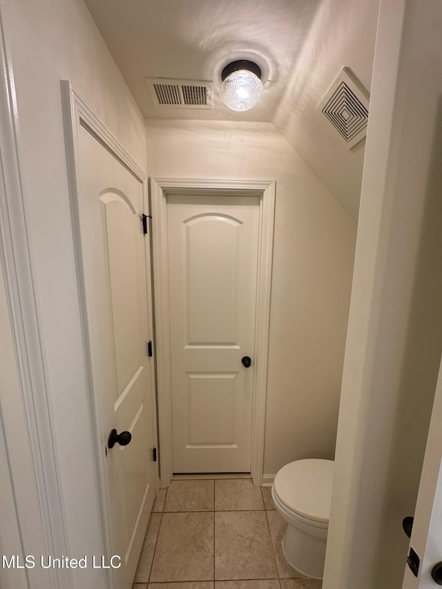 bathroom with lofted ceiling, tile patterned floors, and toilet