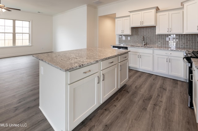 kitchen with white cabinetry, dark hardwood / wood-style floors, tasteful backsplash, and ornamental molding