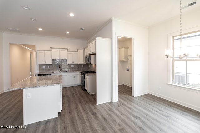 kitchen featuring stainless steel appliances, wood-type flooring, ornamental molding, a center island, and white cabinetry