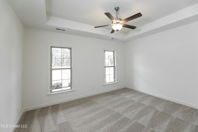 carpeted empty room with a tray ceiling and ceiling fan