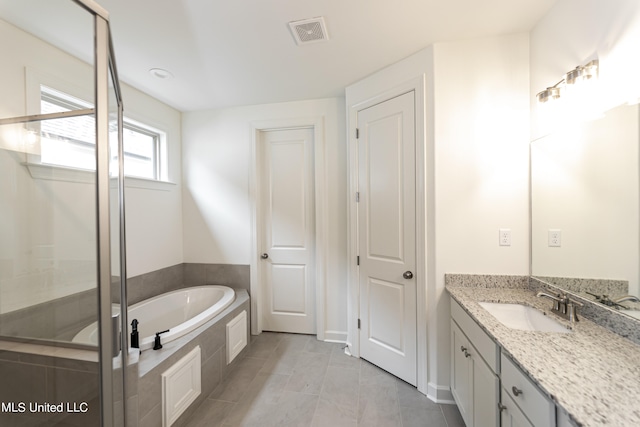 bathroom featuring vanity and tiled tub