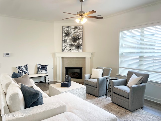 living room featuring light hardwood / wood-style floors, ornamental molding, a tile fireplace, and ceiling fan