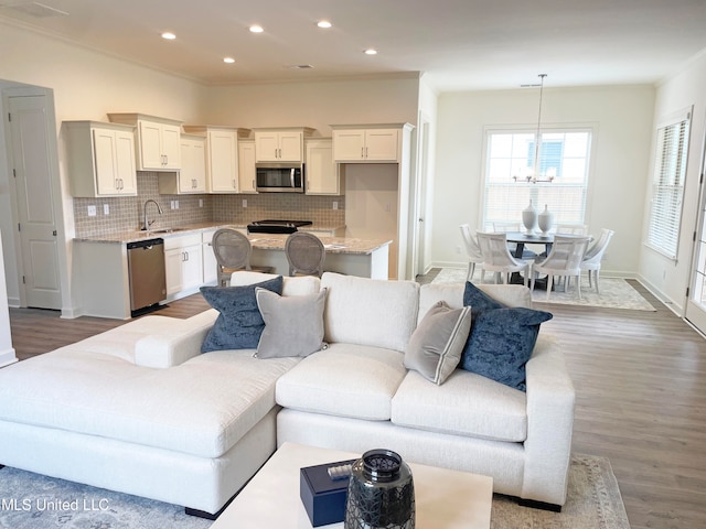 living room with crown molding, sink, and wood-type flooring