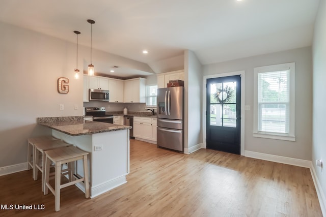 3927 Washington Ave, Gulfport, MS 39507 - kitchen with stainless steel appliances, a peninsula, light wood finished floors, white cabinets, and vaulted ceiling