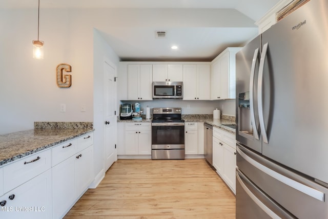 3927 Washington Ave, Gulfport, MS 39507 - kitchen featuring appliances with stainless steel finishes, white cabinets, light wood finished floors, light stone countertops, and decorative light fixtures