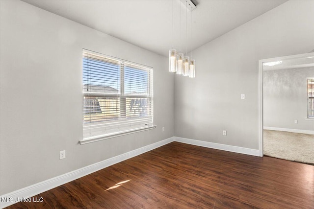 spare room featuring vaulted ceiling and dark hardwood / wood-style flooring