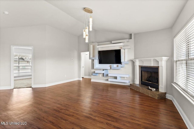 unfurnished living room with dark hardwood / wood-style flooring, vaulted ceiling, a tile fireplace, and a healthy amount of sunlight