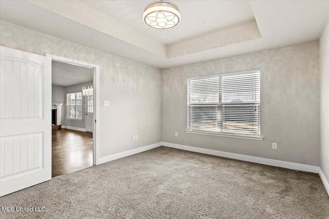 carpeted empty room featuring a raised ceiling